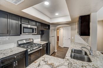 A kitchen with black cabinets and granite countertops.